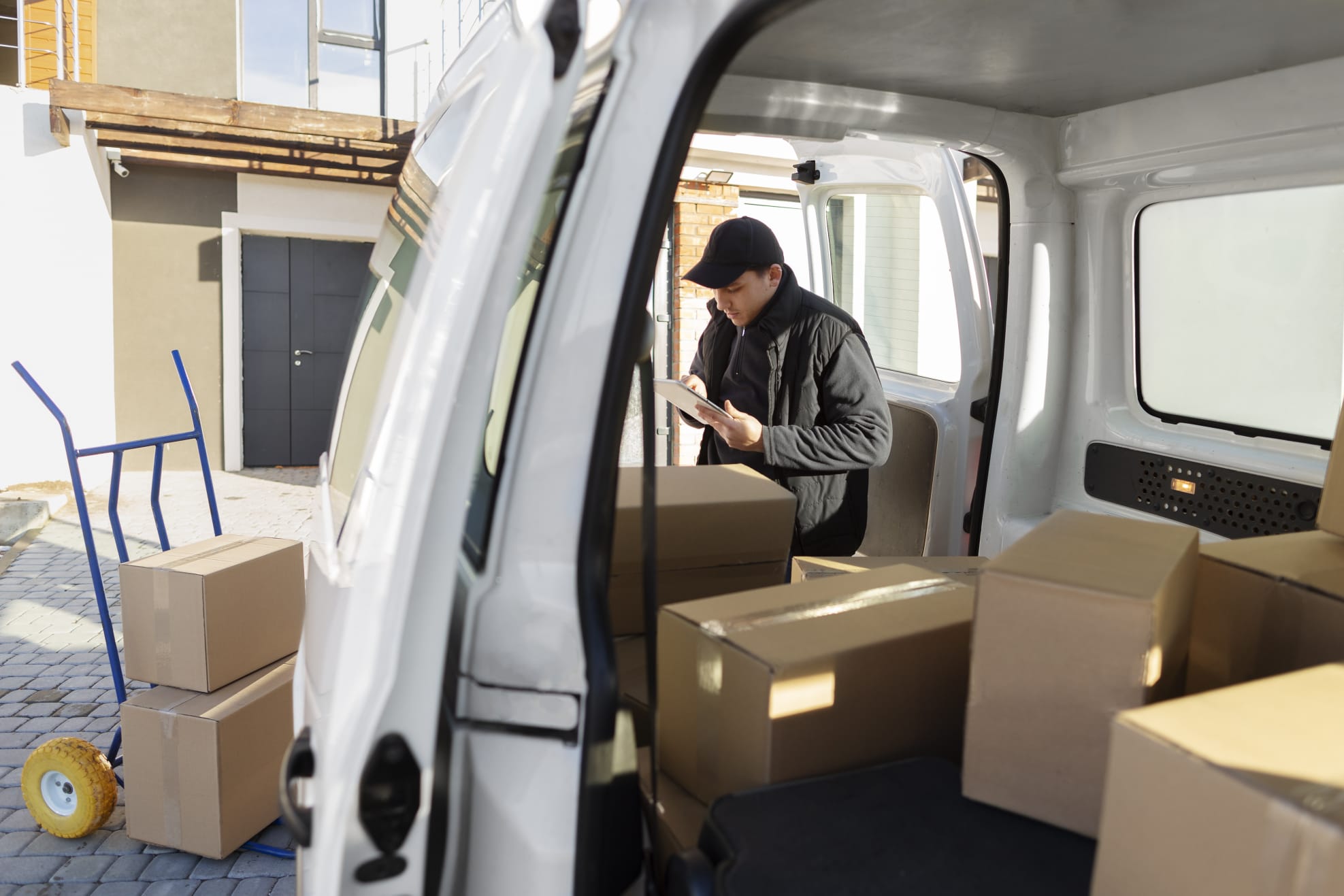 Delivery operative checking a tablet next to a van loaded with parcels
